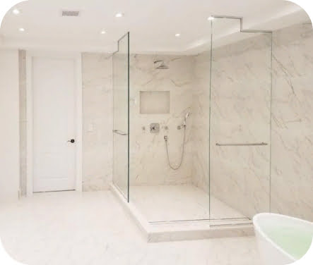 A modern bathroom featuring marble walls and flooring with a glass-enclosed walk-in shower.