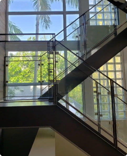 Modern staircase with glass windows showcasing greenery outside.