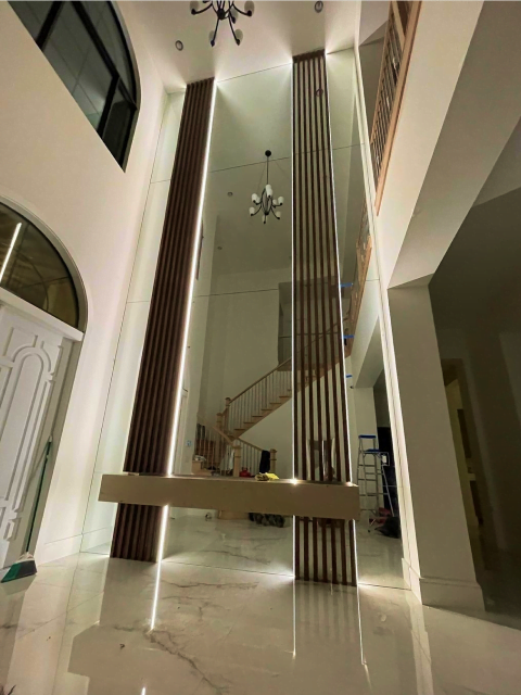 Modern house interior showing a sleek staircase with vertical metal balusters, a custom glass hanging bench, and marble flooring, illuminated by soft lighting.