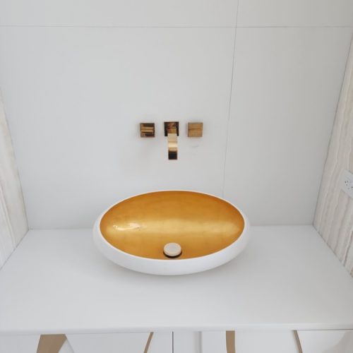 A sleek bathroom vanity with a white countertop featuring an elegant golden oval sink and modern gold fixtures against a white background.