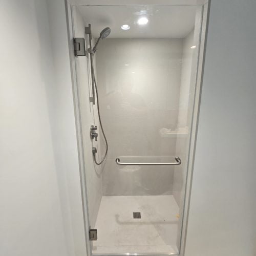 Clear shower door with modern hardware in a minimalist bathroom interior.