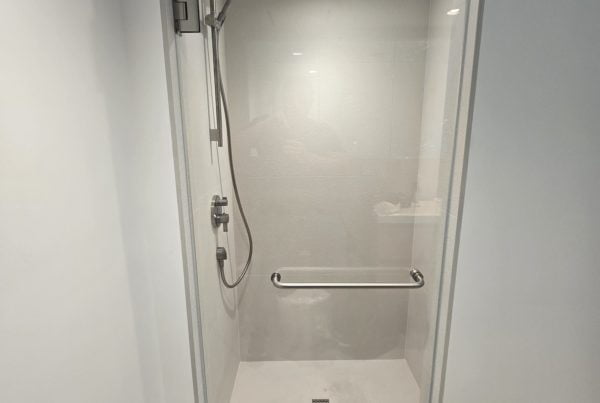 Clear shower door with modern hardware in a minimalist bathroom interior.