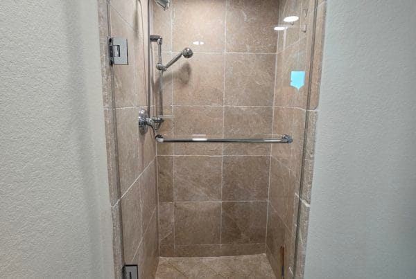 Clear glass shower door in a compact bathroom with beige tiles.